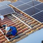Two workers installing solar panels